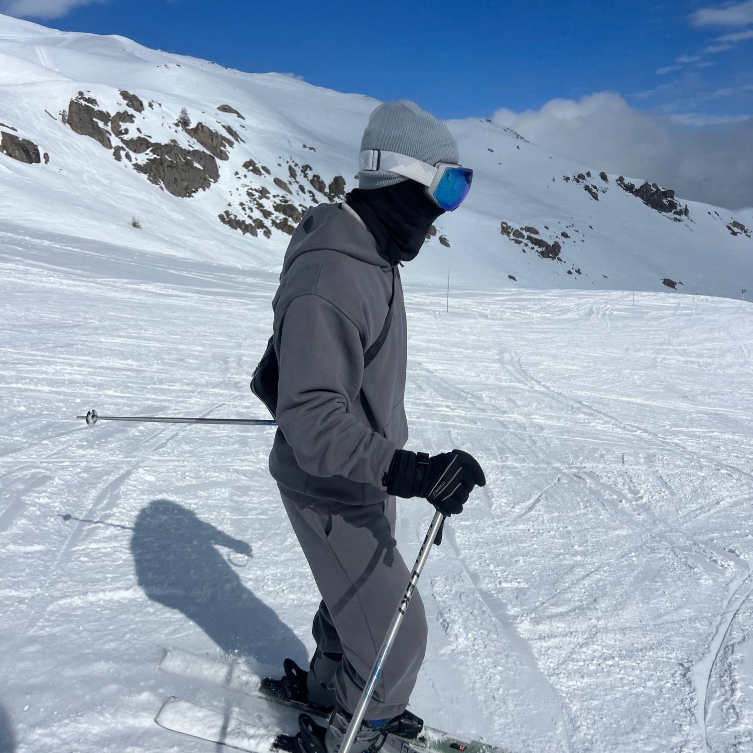 Person skiing on a snowy slope with a clear blue sky wear sos studios
