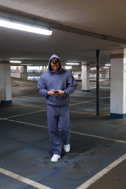 Person wearing a blue sos tracksuit standing in an underground parking lot.