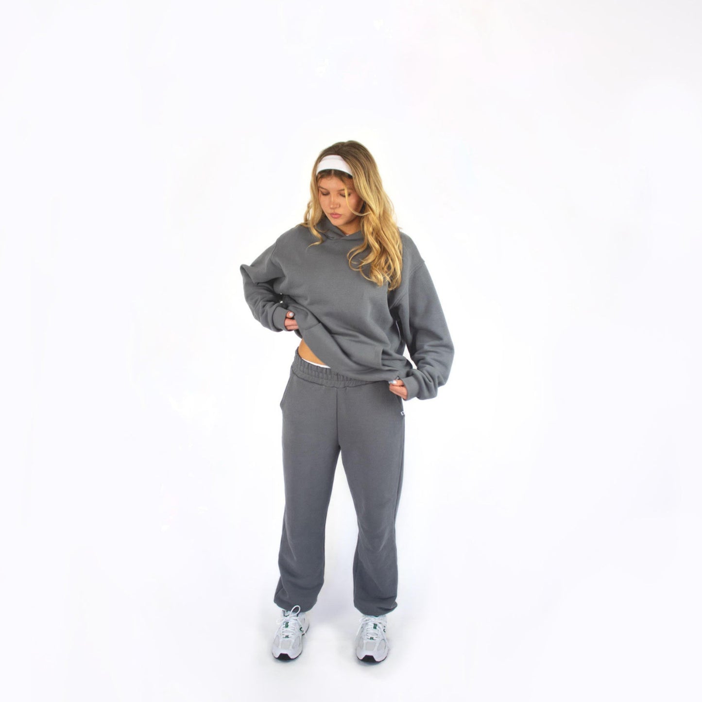 Person wearing a gray sos studios tracksuit on a white background