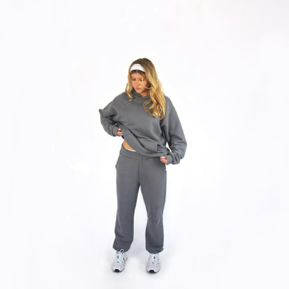 Person wearing a gray sos studios tracksuit on a white background
